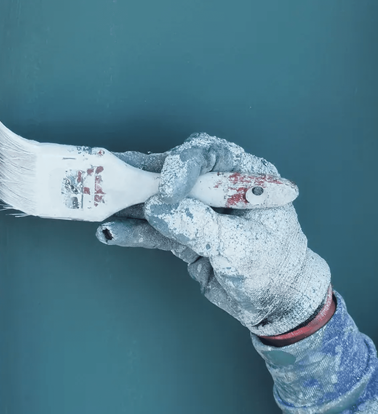 Gloved hand painting wall with brush